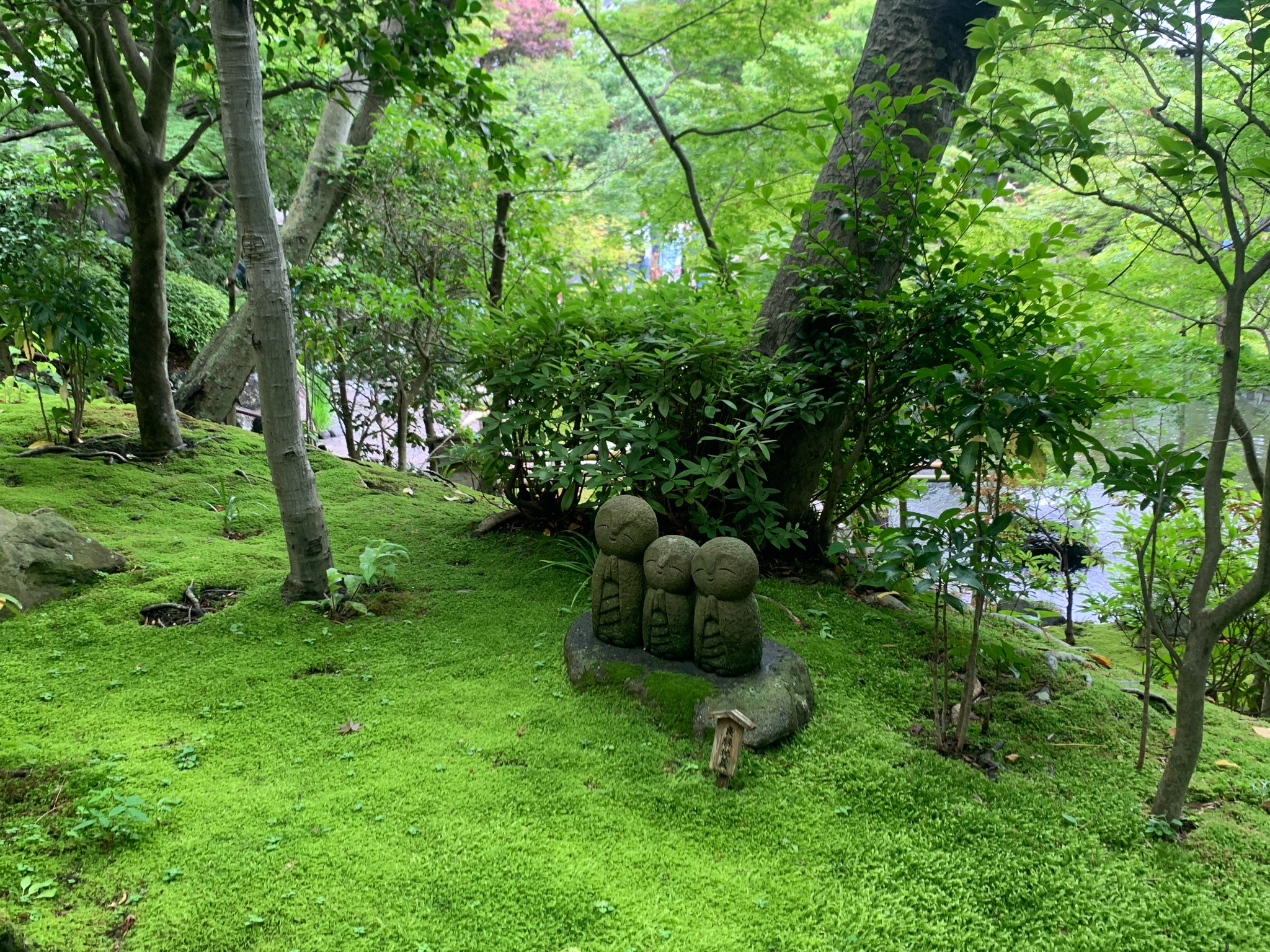 A green garden scene in Japan with three small stone figures